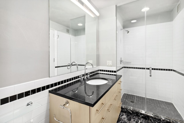 bathroom with vanity, a stall shower, tile walls, and visible vents