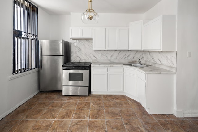 kitchen with a sink, appliances with stainless steel finishes, white cabinets, light countertops, and decorative backsplash