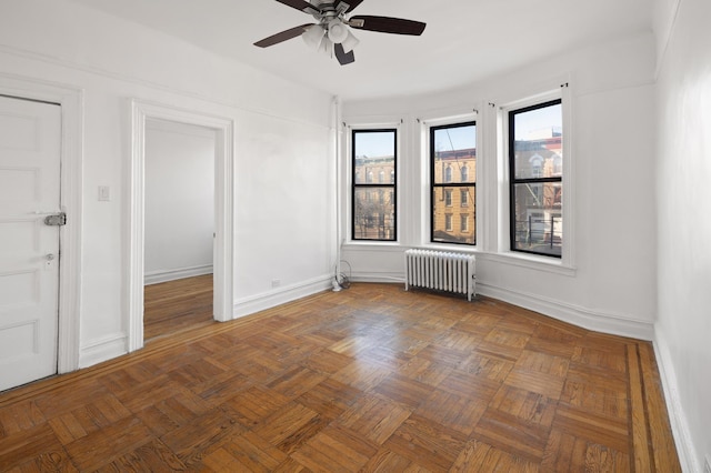 unfurnished room with baseboards, radiator, and ceiling fan