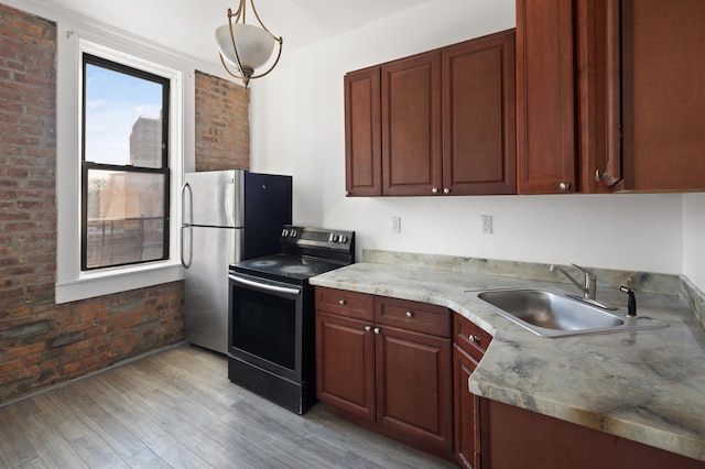 kitchen with a sink, light wood finished floors, brick wall, and range with electric cooktop