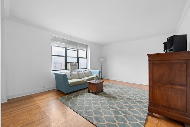 living area with baseboards, crown molding, cooling unit, and light wood-type flooring