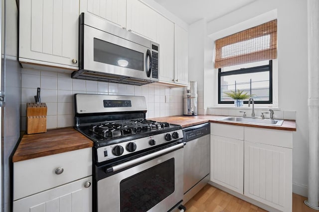 kitchen with appliances with stainless steel finishes, white cabinetry, and wood counters