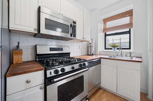 kitchen featuring a sink, appliances with stainless steel finishes, decorative backsplash, and butcher block counters