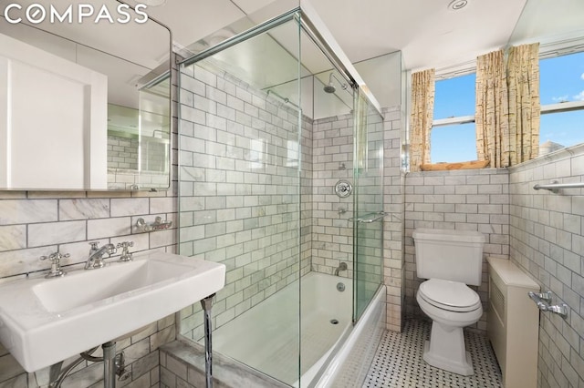 full bathroom featuring sink, tile walls, tile patterned flooring, enclosed tub / shower combo, and toilet