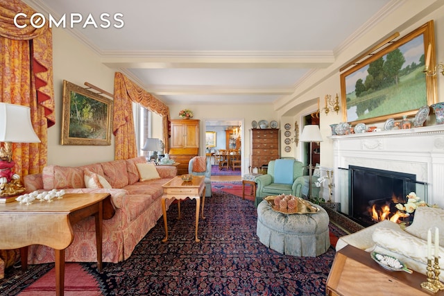 living room with crown molding, a glass covered fireplace, and beamed ceiling