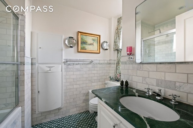 full bath featuring toilet, a wainscoted wall, vanity, and tile walls