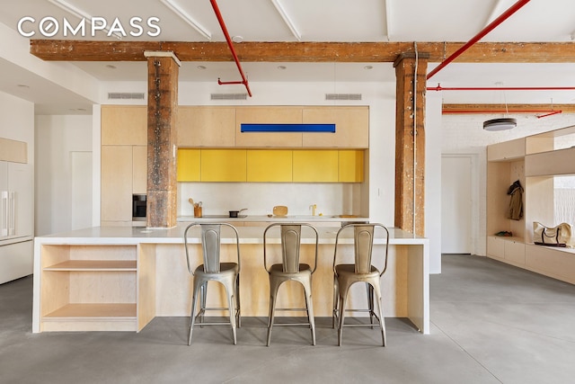 kitchen featuring paneled built in refrigerator, visible vents, concrete flooring, and beamed ceiling