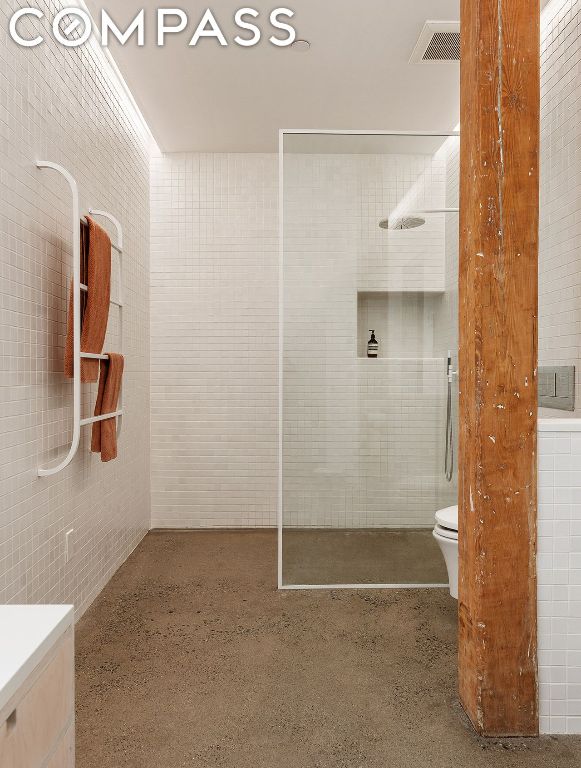 bathroom featuring tile walls, toilet, and walk in shower