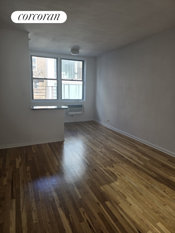 empty room featuring dark hardwood / wood-style flooring and an AC wall unit