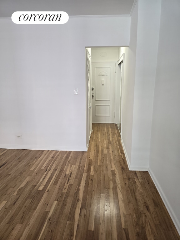 corridor with dark wood-type flooring and ornamental molding