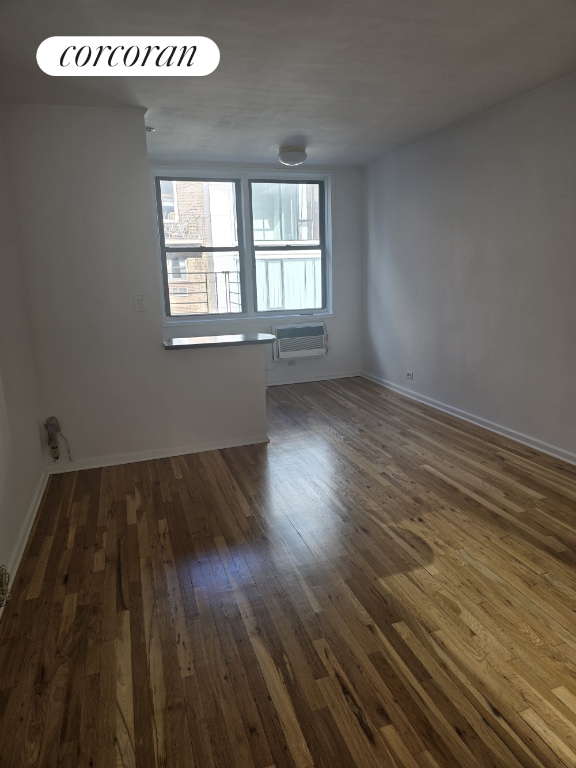 unfurnished room with dark hardwood / wood-style flooring and a wall mounted air conditioner