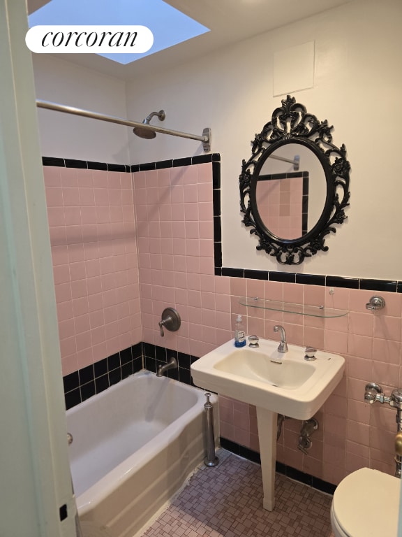 bathroom featuring tile walls, tiled shower / bath, tile patterned floors, and toilet