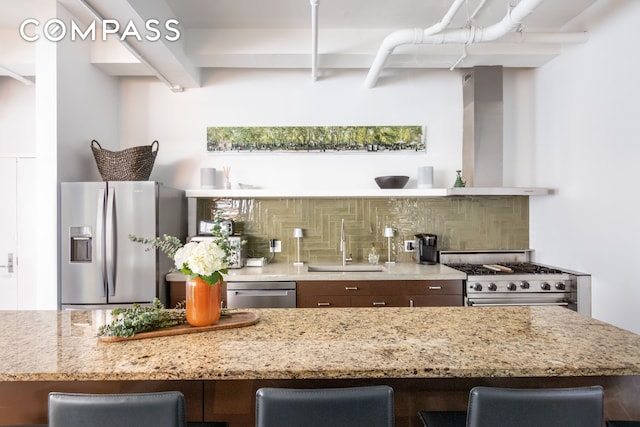 241 W 36th St Unit 7R, New York City, NY 10018 - kitchen with stainless steel appliances, decorative backsplash, light stone counters, and a breakfast bar area