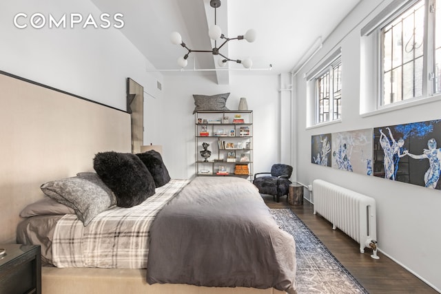 bedroom featuring a chandelier, radiator, and wood finished floors