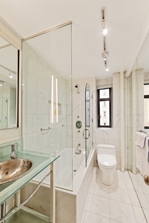 full bathroom with tile walls, sink, tiled shower / bath combo, and toilet