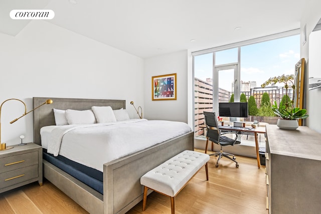 bedroom featuring a wall of windows and light hardwood / wood-style floors