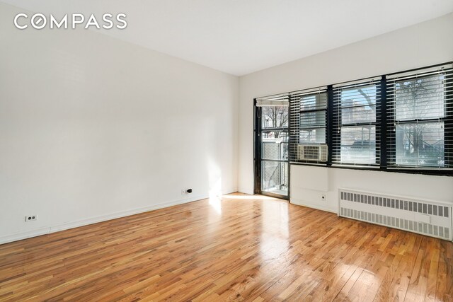 empty room featuring radiator heating unit and light wood-type flooring