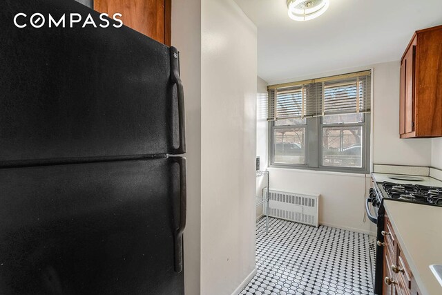 kitchen with black refrigerator, radiator, and gas stove