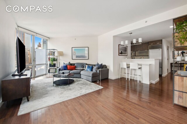 living room with expansive windows, wood-type flooring, and baseboards