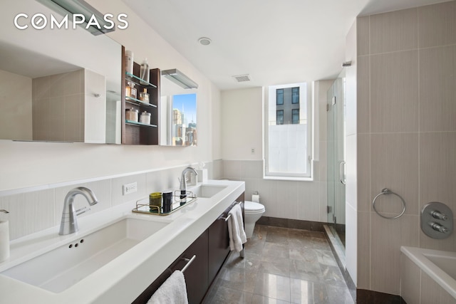 bathroom with visible vents, a sink, a tile shower, and toilet