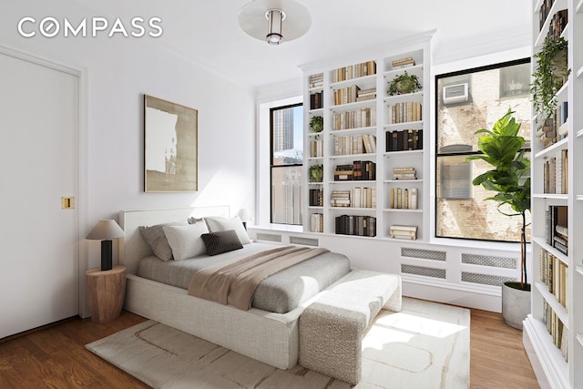 bedroom with ornamental molding and wood finished floors