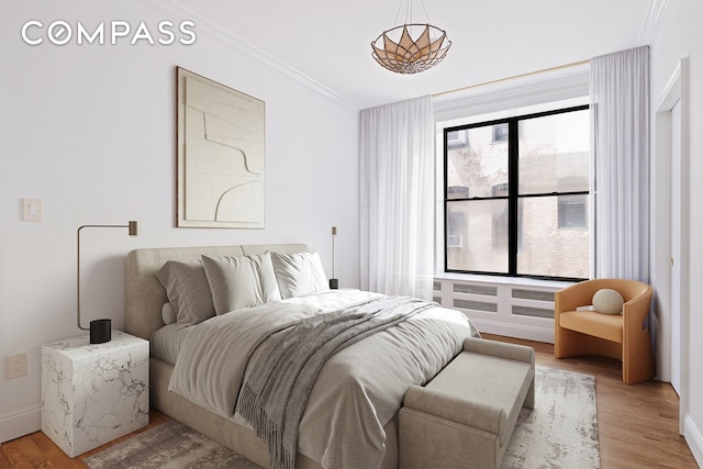 bedroom with crown molding, light wood-style flooring, and baseboards