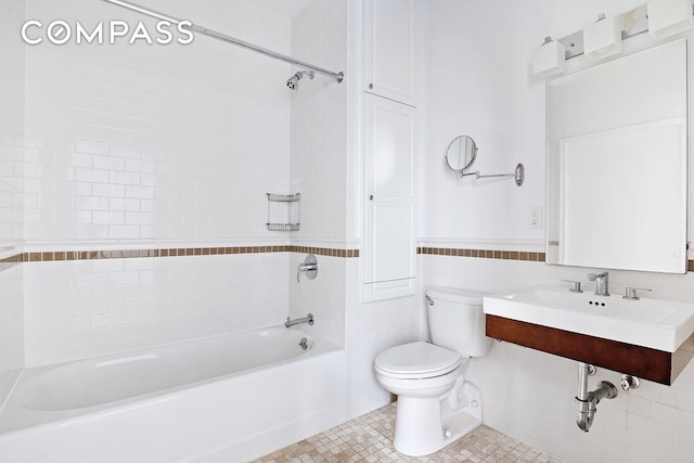 full bathroom with toilet, a wainscoted wall, tile patterned floors, washtub / shower combination, and tile walls