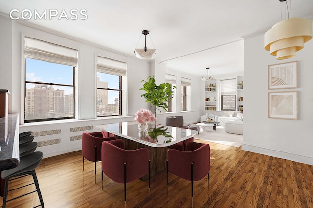 dining room featuring built in features, crown molding, light wood-style flooring, and baseboards