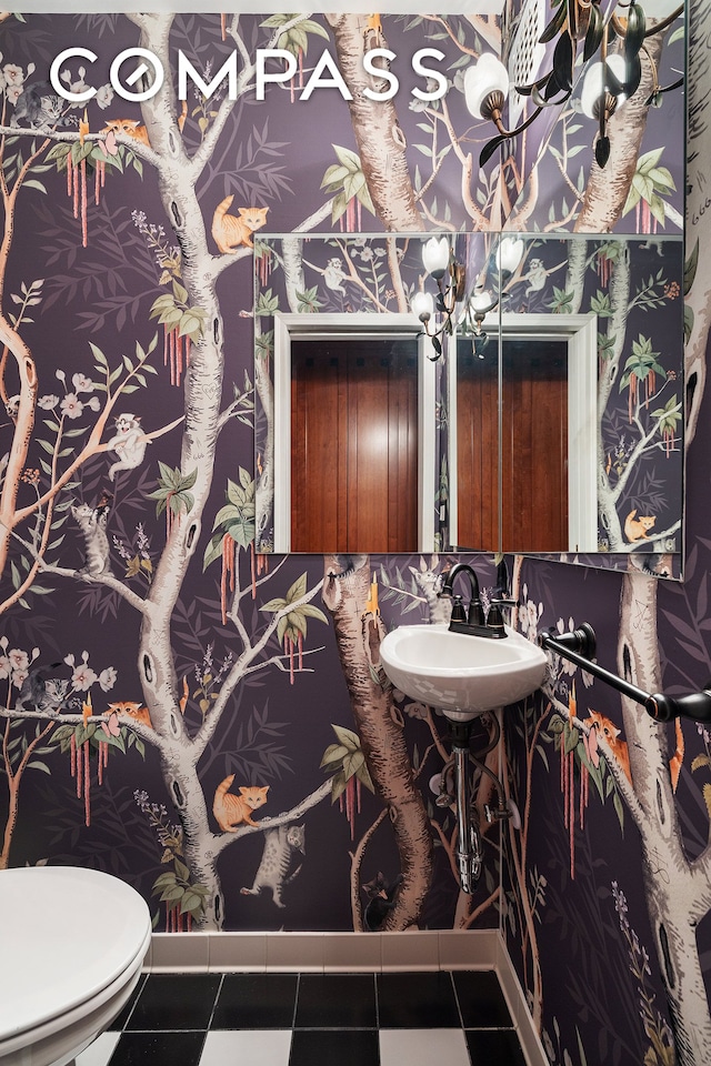 half bath featuring a sink, toilet, and tile patterned floors