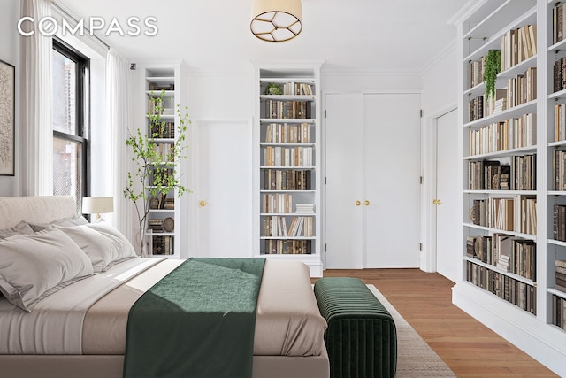 bedroom with access to outside, a closet, crown molding, and wood finished floors