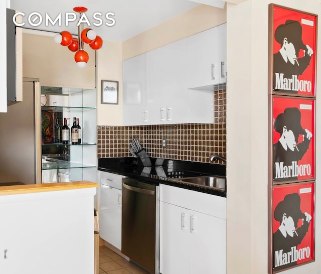 kitchen with a sink, dark countertops, tasteful backsplash, appliances with stainless steel finishes, and white cabinets