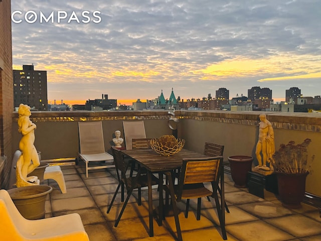 patio terrace at dusk with a city view and outdoor dining space