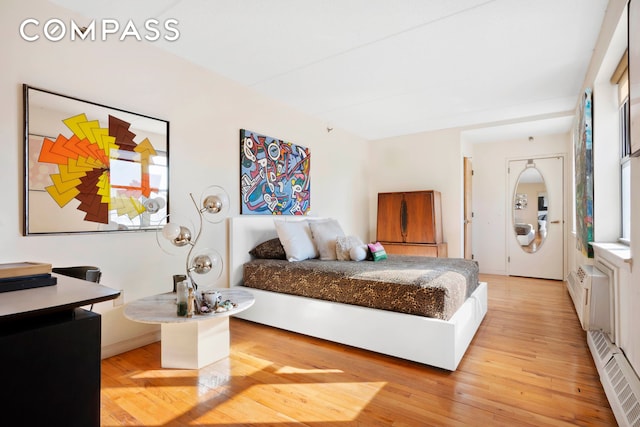 bedroom featuring light wood-style flooring and a baseboard radiator