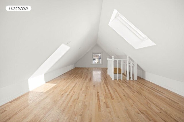 bonus room with lofted ceiling with skylight, visible vents, and wood finished floors