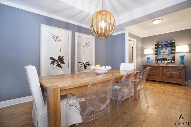 dining room with hardwood / wood-style flooring, ornamental molding, and an inviting chandelier