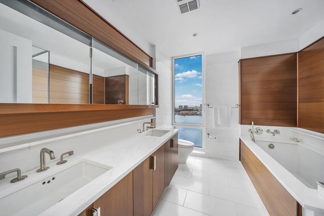 bathroom with toilet, a garden tub, tile patterned flooring, and double vanity