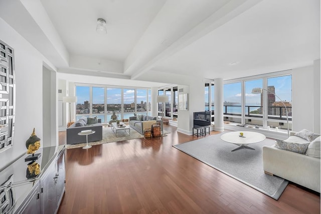 living room with a water view, wood finished floors, and beamed ceiling