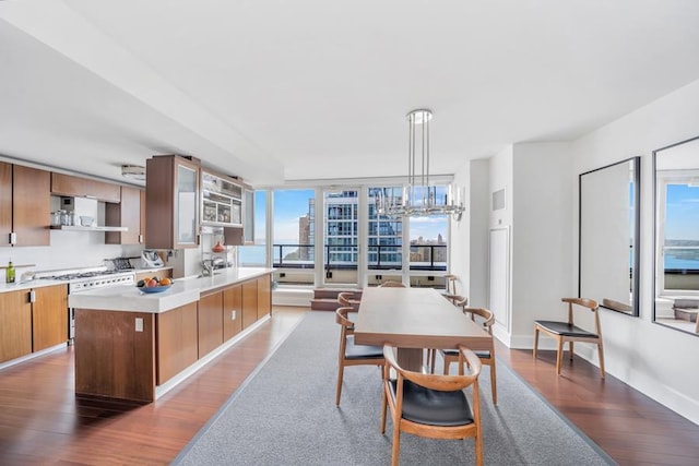 kitchen featuring white range with gas cooktop, wood finished floors, light countertops, pendant lighting, and wall chimney exhaust hood