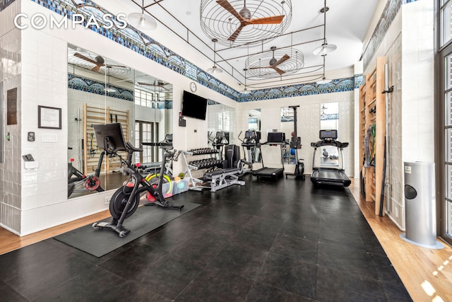 gym with a ceiling fan and a towering ceiling