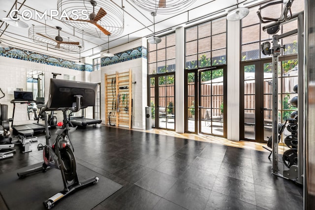 exercise room featuring plenty of natural light, a towering ceiling, and ceiling fan