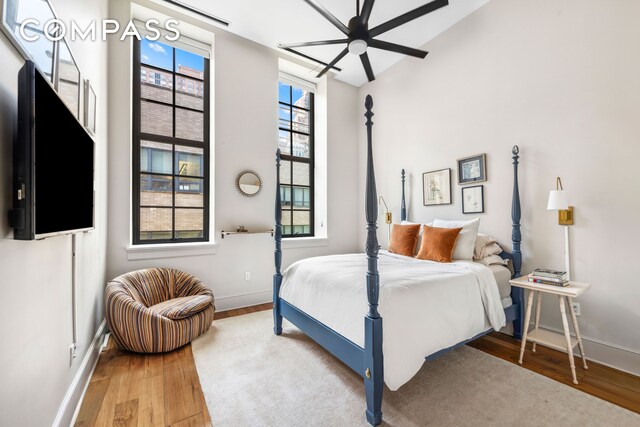 gym with ceiling fan, a towering ceiling, and a wall of windows