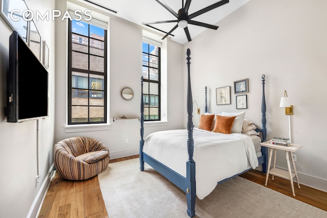 bedroom featuring wood finished floors, baseboards, a ceiling fan, and lofted ceiling