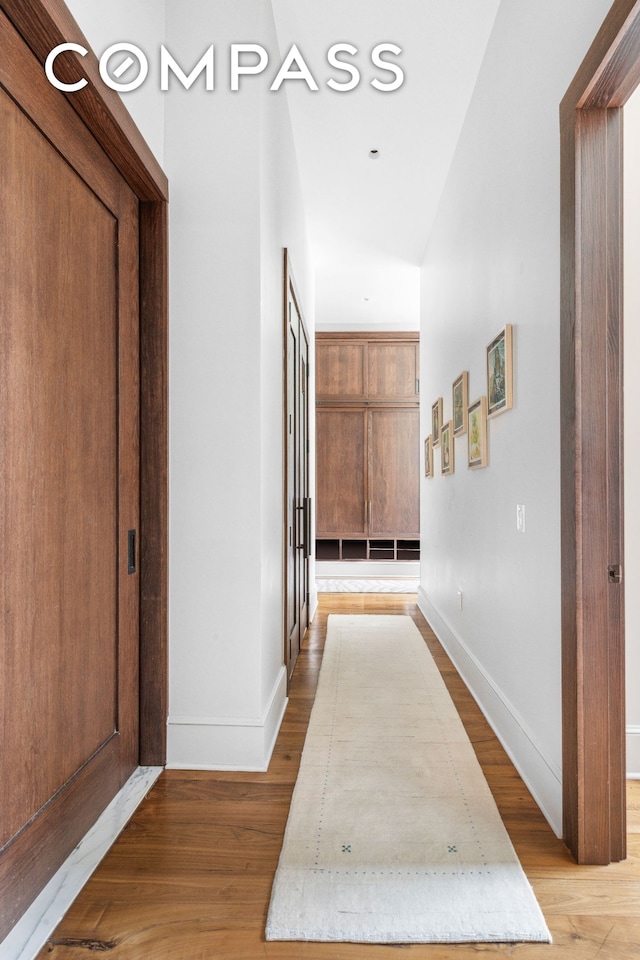 hall featuring baseboards and light wood-type flooring