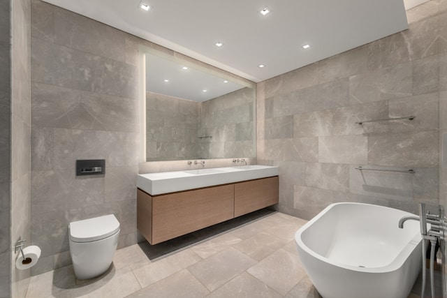 bathroom featuring tile walls, vanity, a tub, and toilet