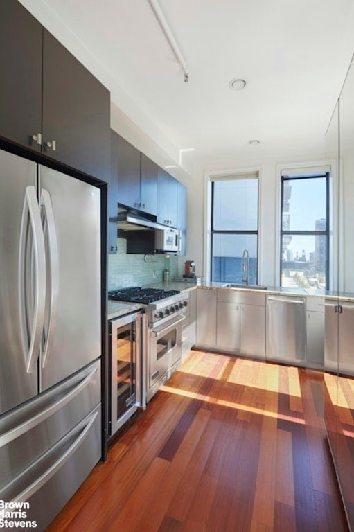 kitchen with appliances with stainless steel finishes, sink, wine cooler, and dark hardwood / wood-style floors