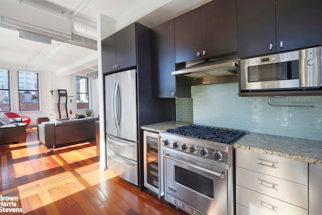 kitchen with backsplash, stainless steel appliances, wine cooler, dark hardwood / wood-style flooring, and wall chimney exhaust hood