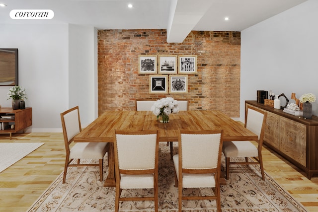 dining space featuring beamed ceiling, brick wall, and light hardwood / wood-style flooring