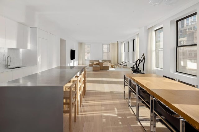 kitchen featuring white cabinetry, sink, tasteful backsplash, and light hardwood / wood-style flooring