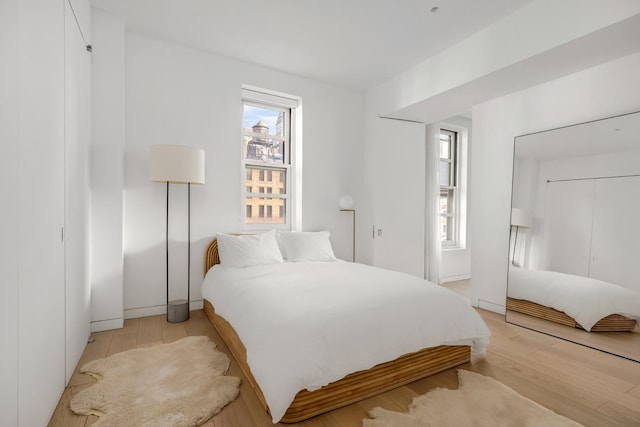 bedroom featuring light wood finished floors and multiple windows