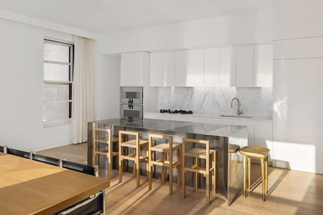 kitchen with modern cabinets, a sink, stainless steel oven, and white cabinets